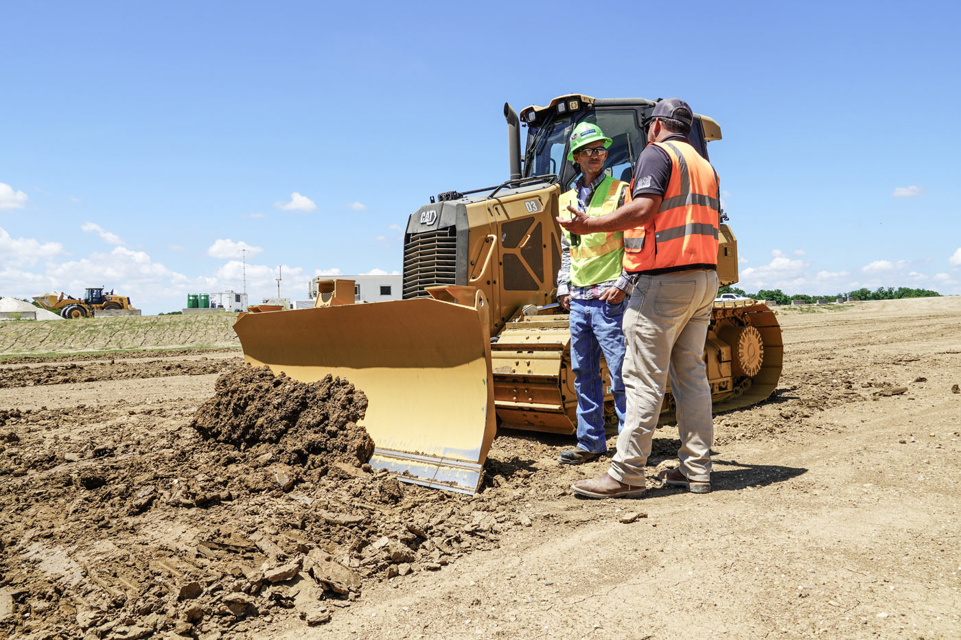 Two crew members talking beside a dozer on a job site