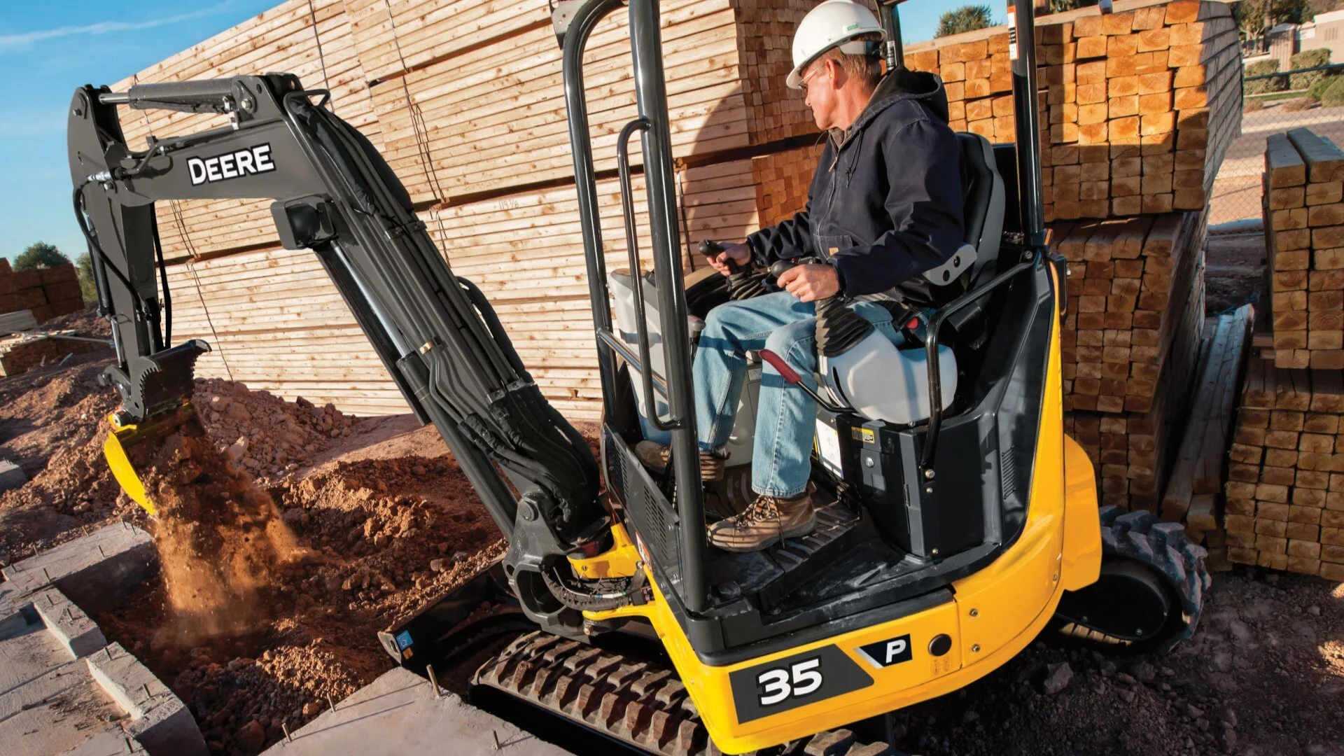 An operator at the controls of a compact excavator